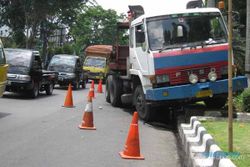Rem blong, truk trailer bermuatan besi tabrak pembatas jalan