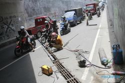 FOTO PERBAIKAN UNDERPASS : Pekerja Memperbaiki Besi Penutup Saluran Air Underpass Makam Haji Sukoharjo