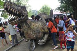 FOTO LIBURAN : Menaiki wahana motor berbentuk dinosaurus